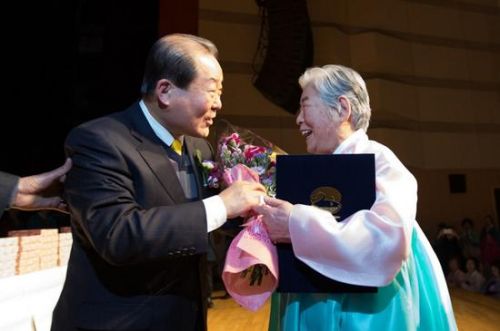 88岁的辛福顺奶奶正从麻浦区厅长朴兴协手中接过奖状和鲜花。